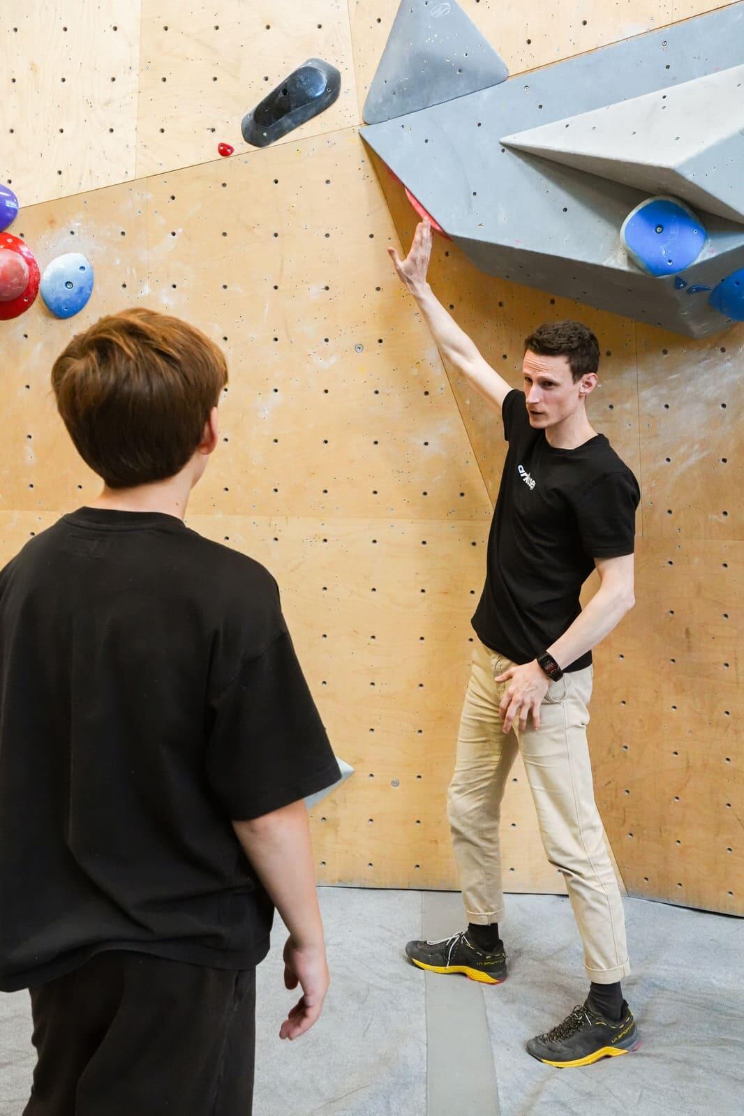 Parent assis au bord du tapis, enfant en haut d'un bloc kids